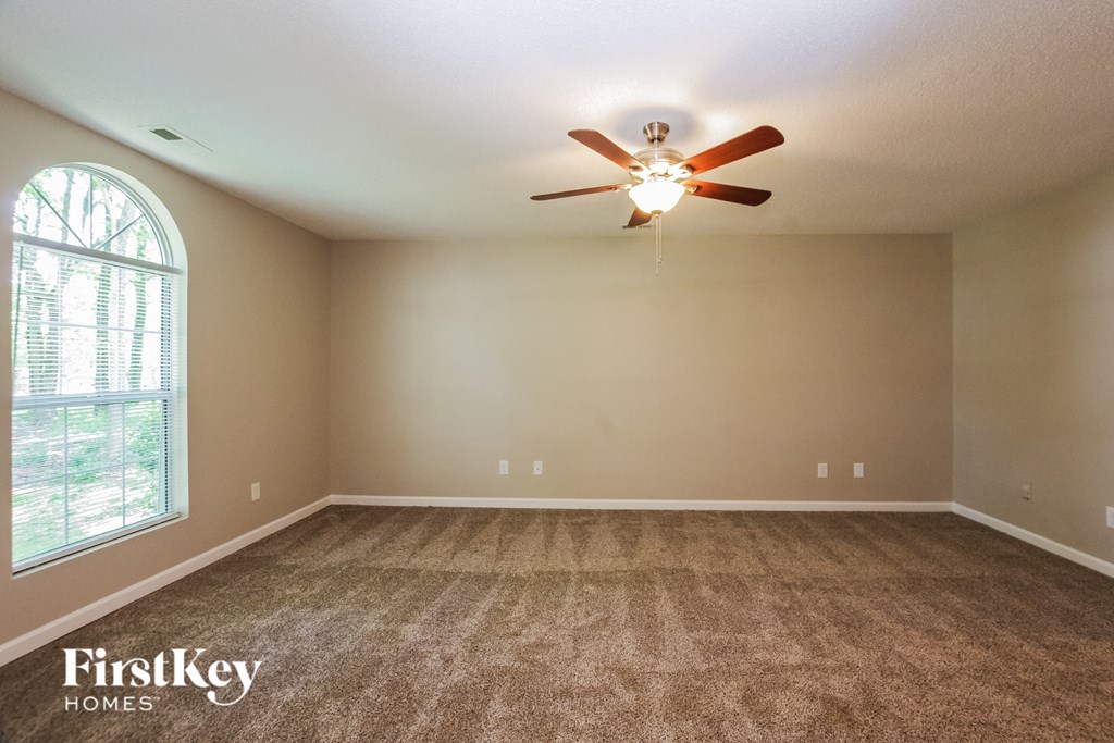 an empty living room with a ceiling fan and a window