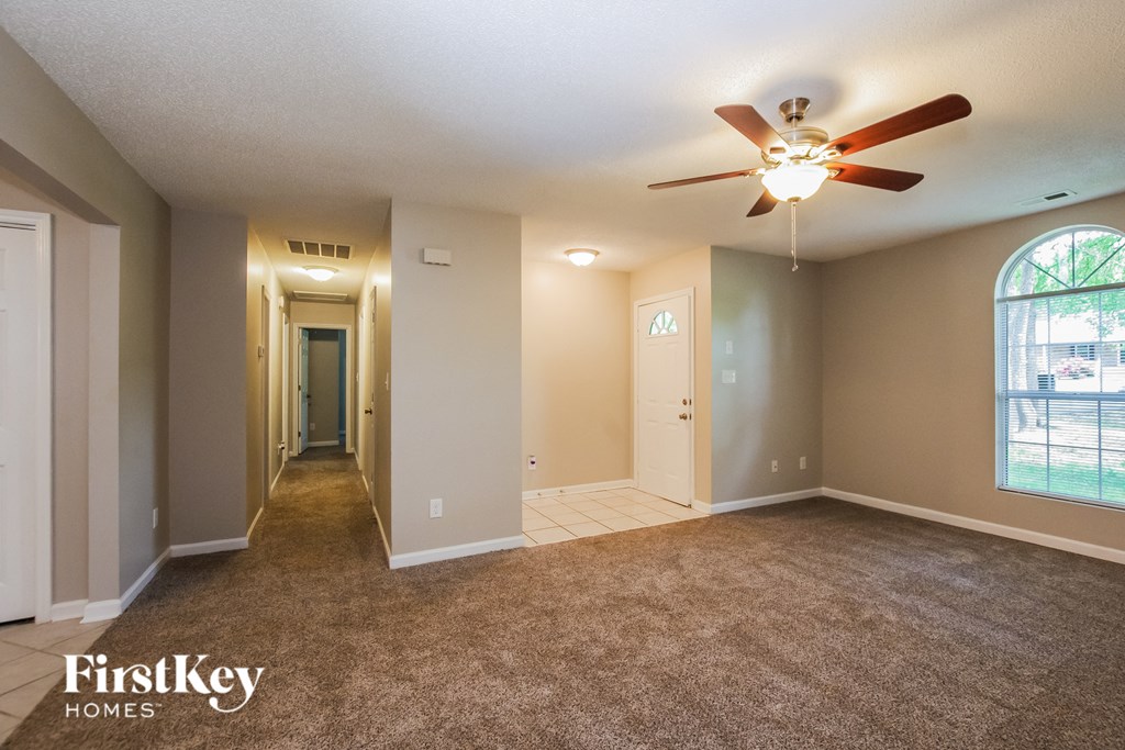 an empty living room with carpet and a ceiling fan