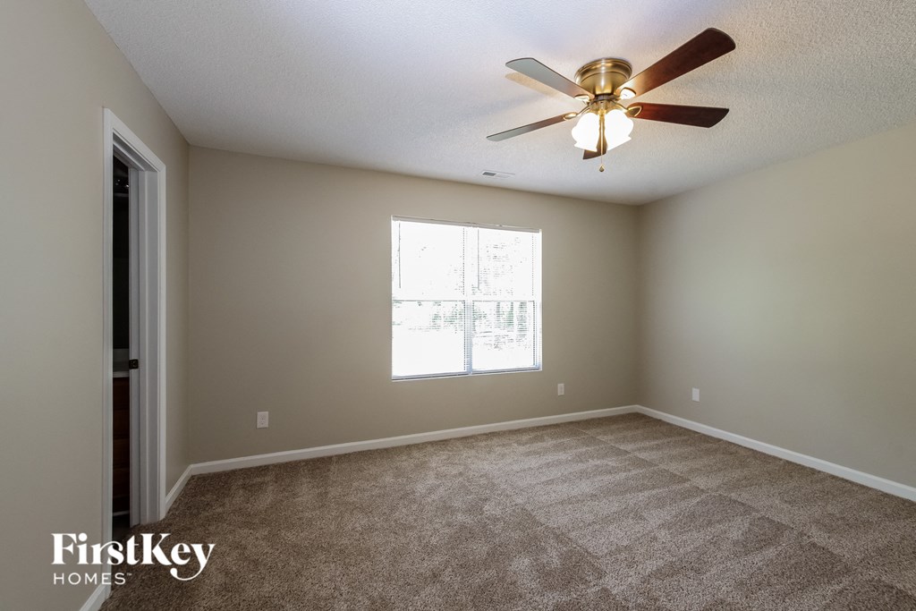an empty living room with a ceiling fan and a window