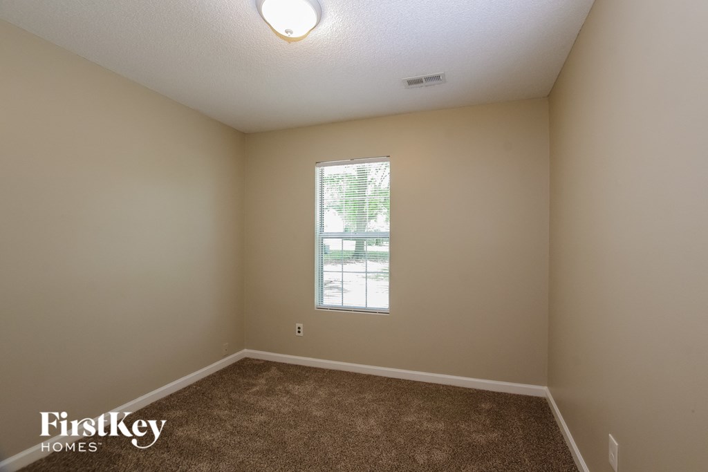 the living room of an empty house with carpet and a window