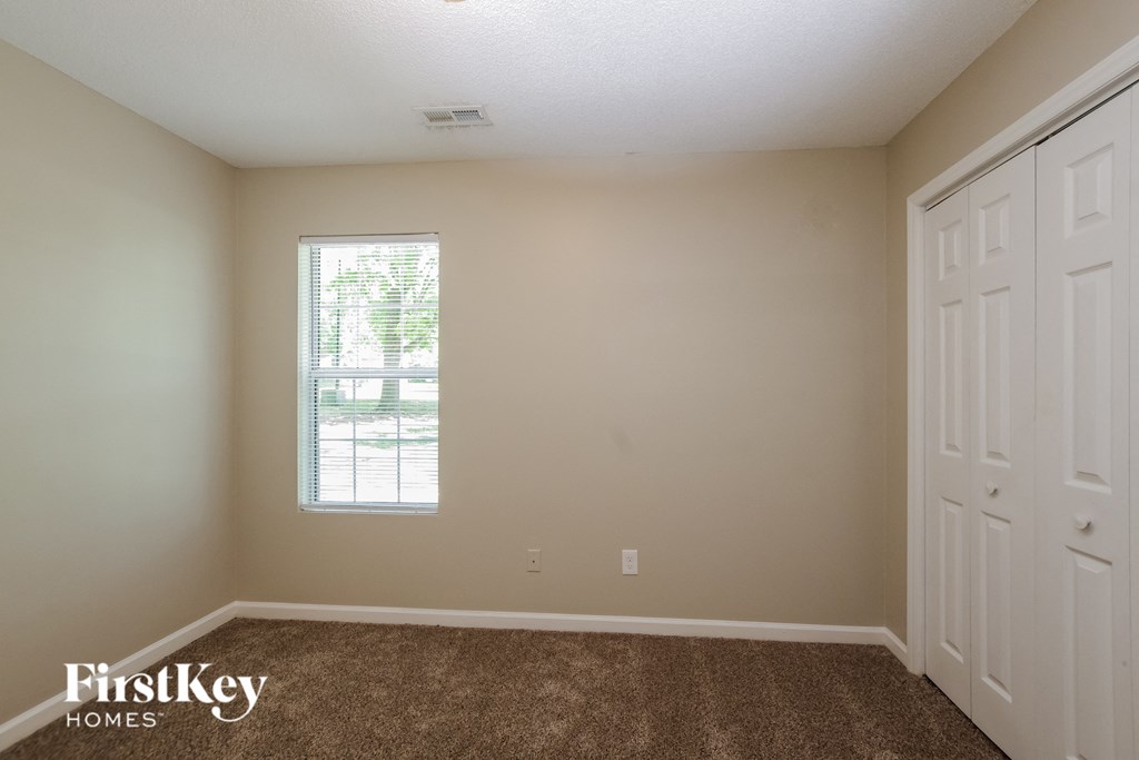 the living room of an empty house with carpet and a window
