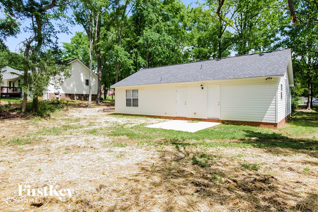 a backyard with a small white house and a garage
