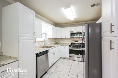 A kitchen with white cabinets and a black refrigerator.