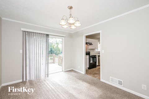 a living room with carpet and a sliding glass door to the kitchen