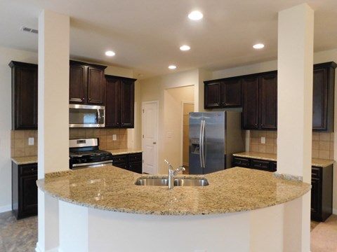 a kitchen with granite counter tops and black cabinets
