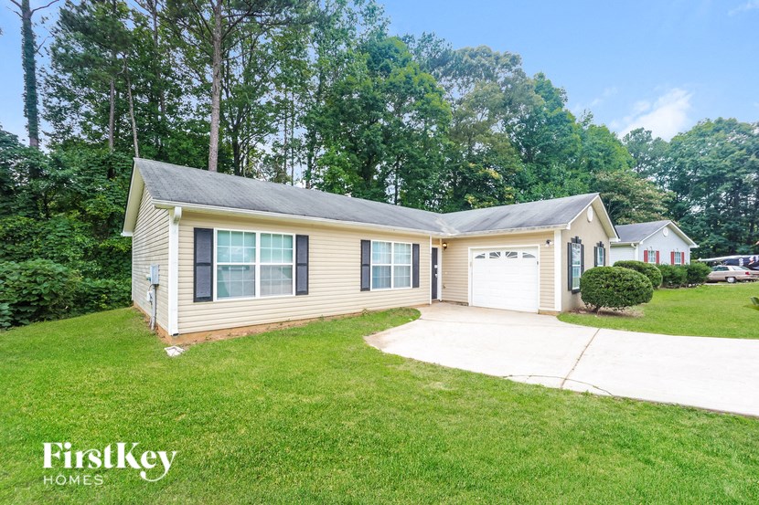a small yellow house with a driveway and a lawn