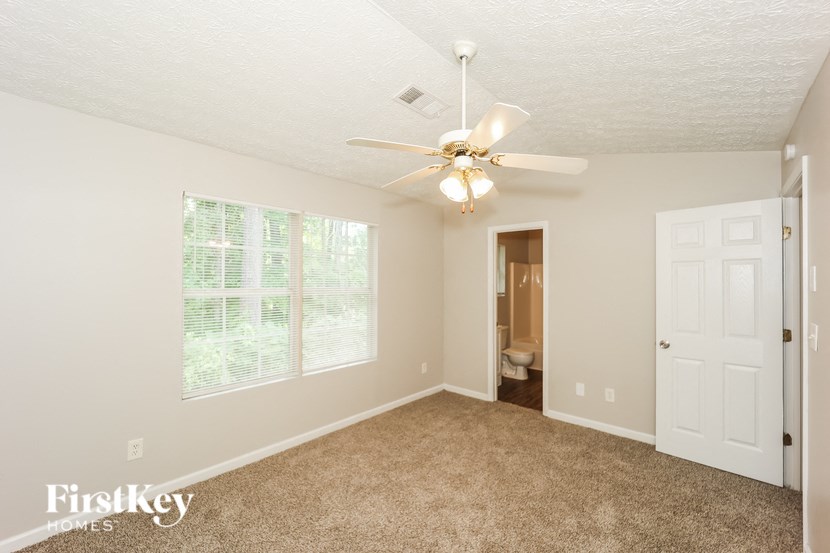 a bedroom with a ceiling fan and a door to a bathroom