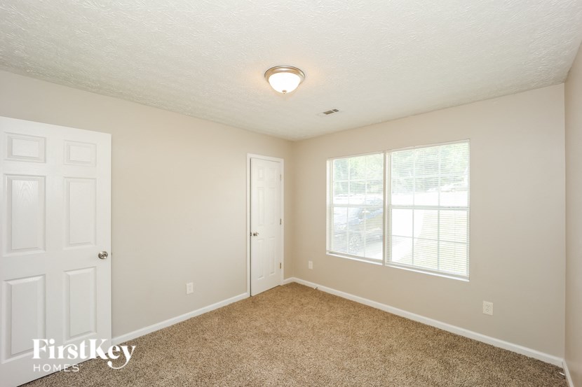 a bedroom with a door and a window and a carpeted floor