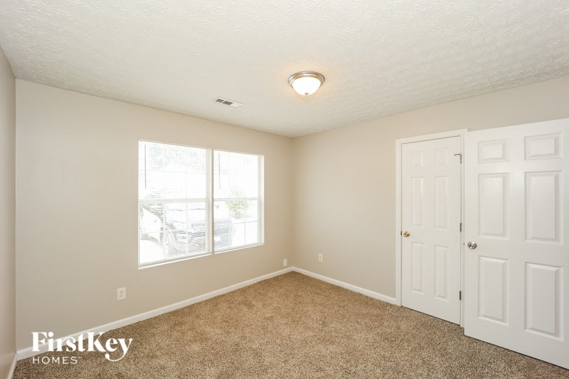 a bedroom with a white door and a window and carpeting