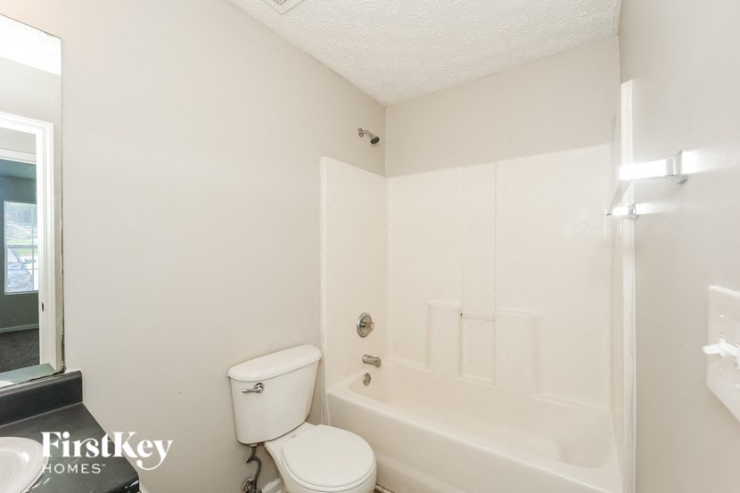a white bathroom with a toilet and a tub