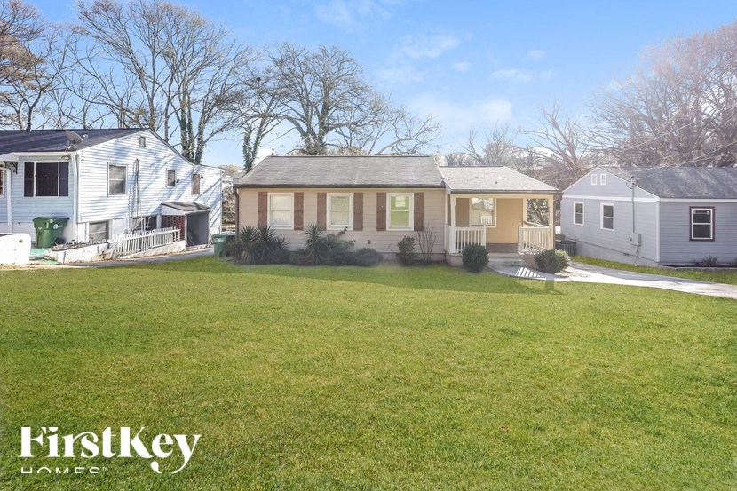 A grassy field with a house and a trailer in the background.
