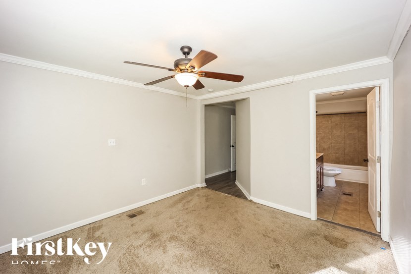 A bedroom with a carpeted floor and a ceiling fan.