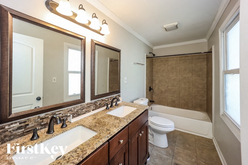 A bathroom with a granite countertop and a large mirror above the sink.