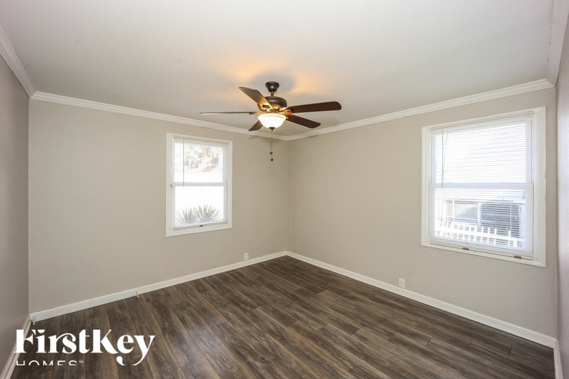 A room with a ceiling fan and two windows.