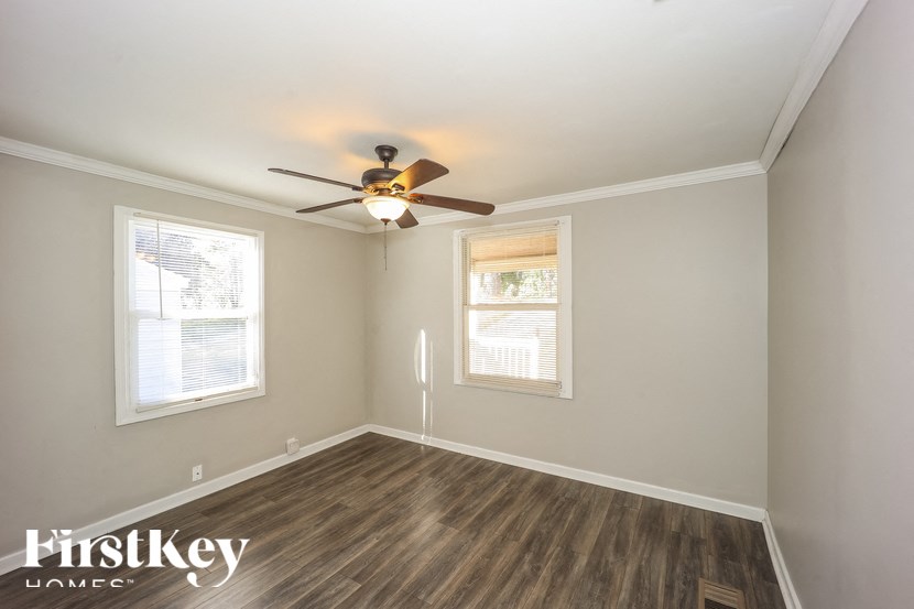 A room with a ceiling fan and two windows.
