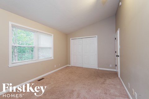 a bedroom with beige carpet and a white door and window