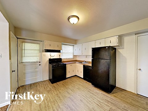 A kitchen with black appliances and wooden floors.