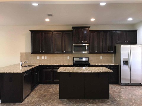 A kitchen with dark brown cabinets and granite countertops.