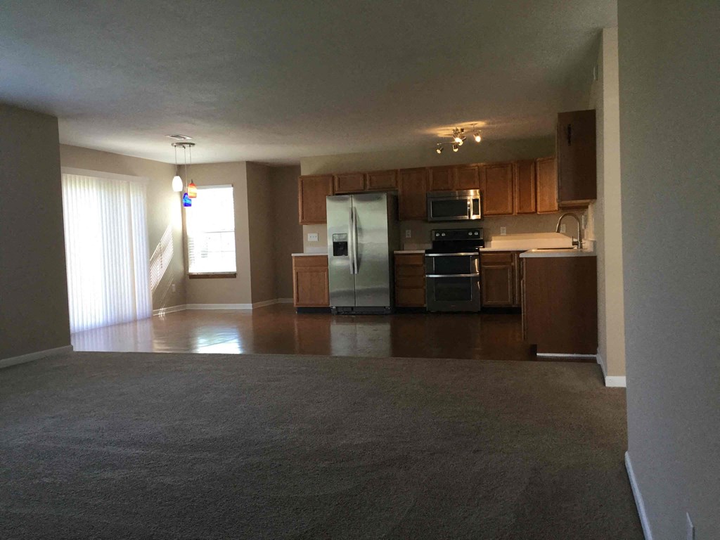 A kitchen with a refrigerator, microwave, and oven.