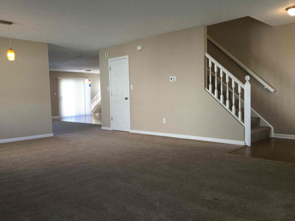 A room with a staircase and a door leading to another room.