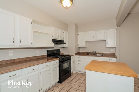 A kitchen with white cabinets and a wooden island.