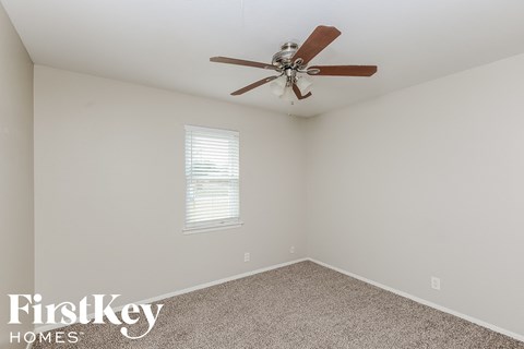 the living room has a ceiling fan and beige carpet