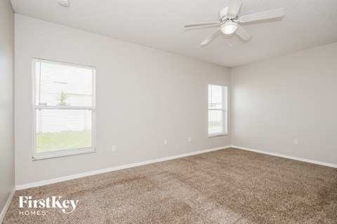 a spacious living room with carpet and a ceiling fan