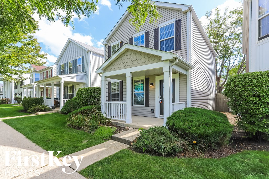 a white house with a porch and a sidewalk in front of it