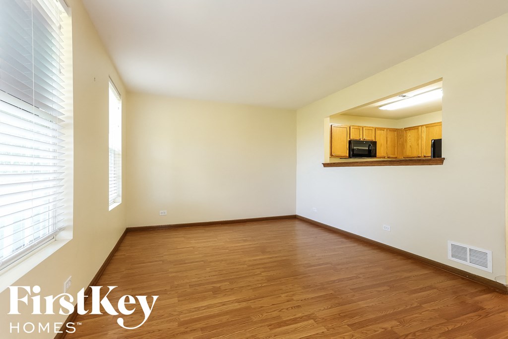 an empty living room with wood flooring and a window