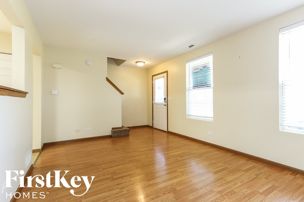 a living room with wood floors and white walls and a door