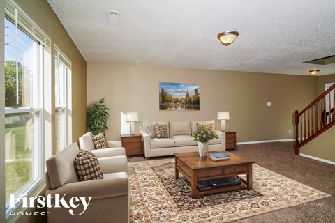 A living room with a couch, a chair, a coffee table, and a painting on the wall.