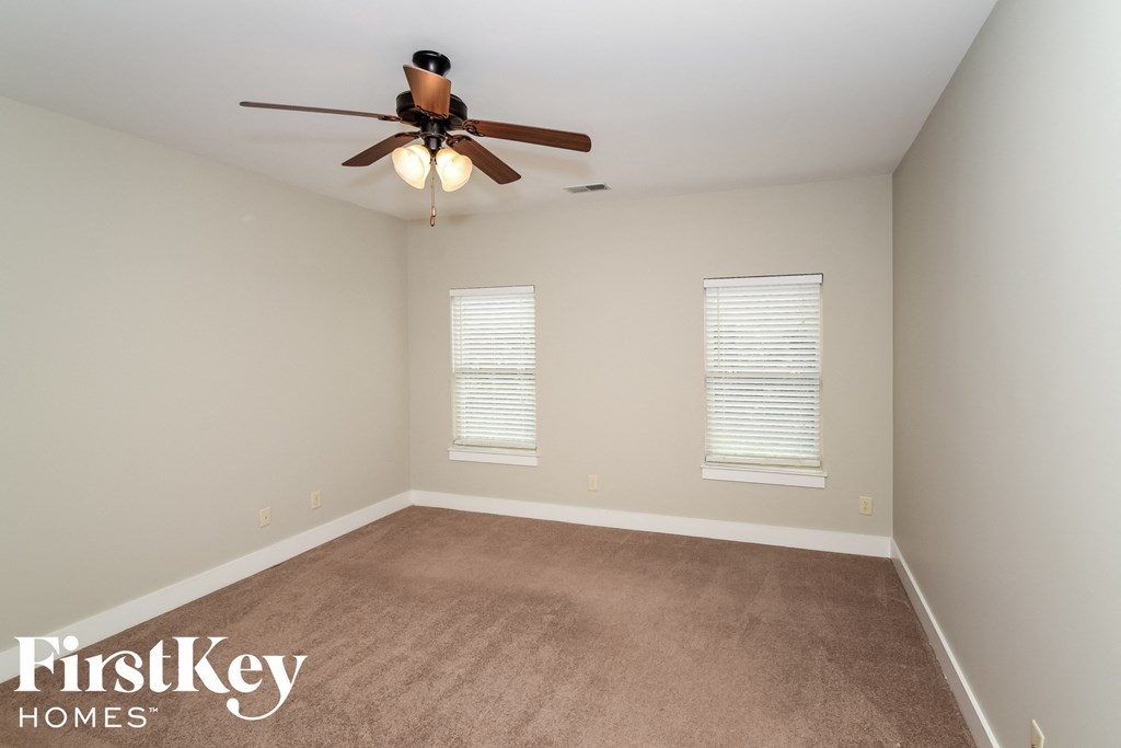 an empty room with a ceiling fan and two windows