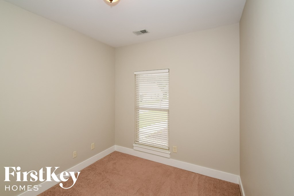 a bedroom with white walls and a window with blinds
