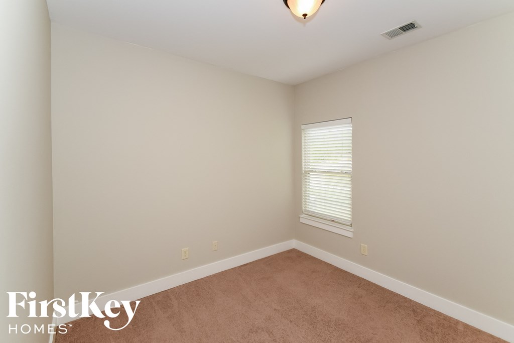 a bedroom with beige carpet and white walls and a window