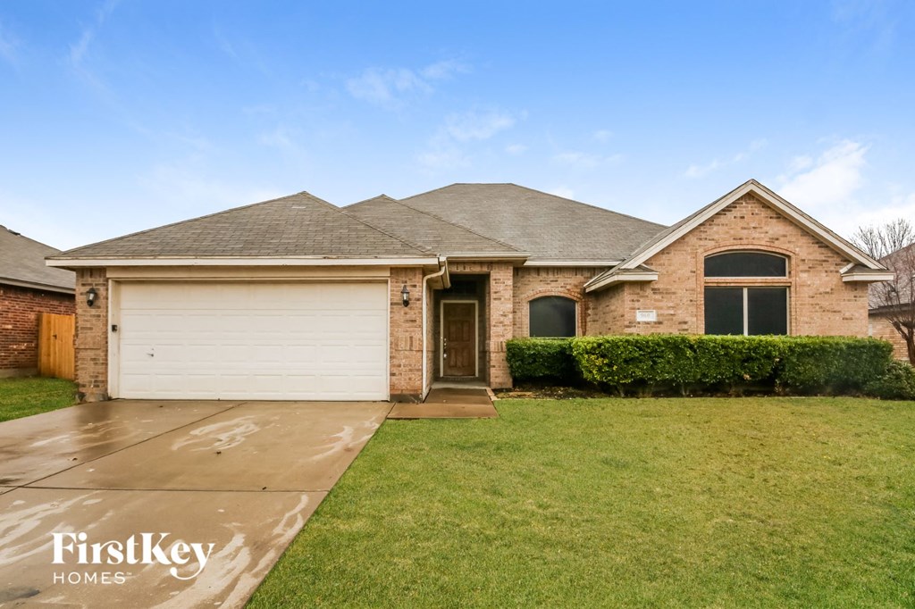a brick house with a white garage door and a lawn
