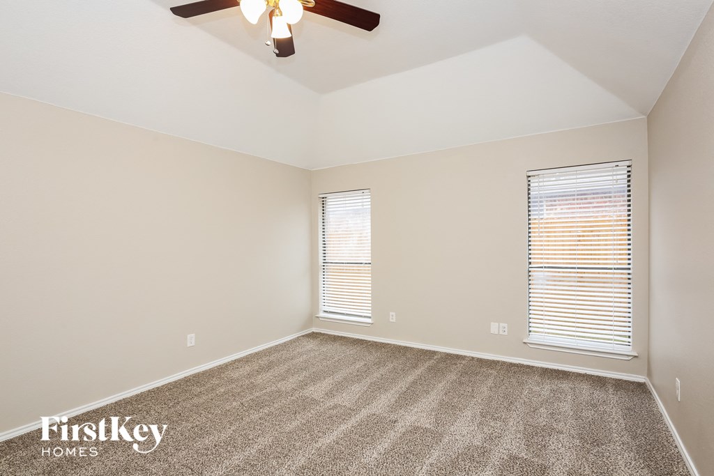 the spacious living room with carpeting and a ceiling fan
