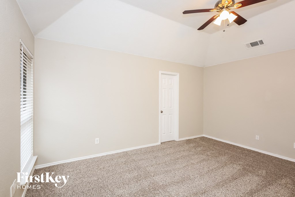 the living room of an empty home with a ceiling fan