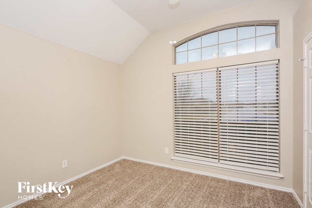 the second bedroom has a large window and carpeted flooring