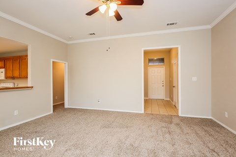 a spacious living room with carpet and a ceiling fan
