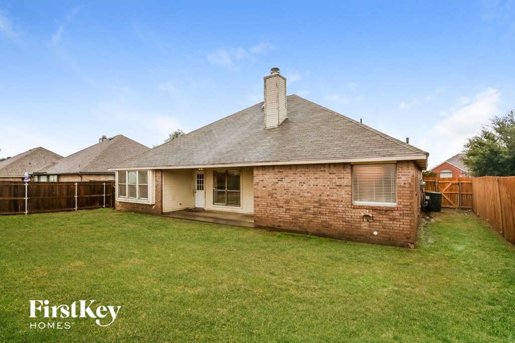 a backyard with a brick house and a wooden fence