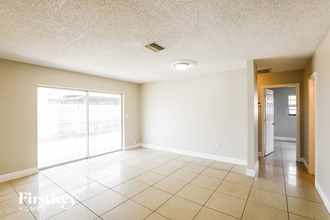 A spacious room with a sliding glass door leading to a balcony.