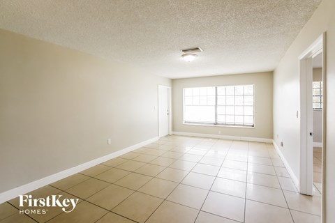A spacious room with a tile floor and a window letting in natural light.