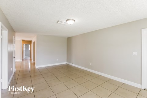 A spacious room with a tiled floor and a doorway leading to another room.