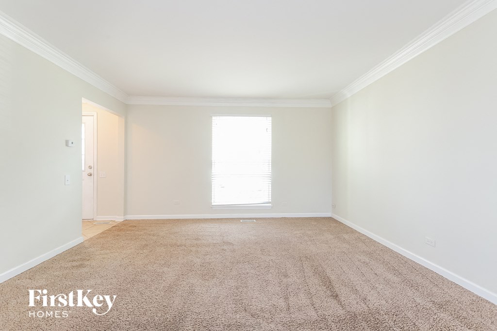 a empty living room with white walls and a carpet