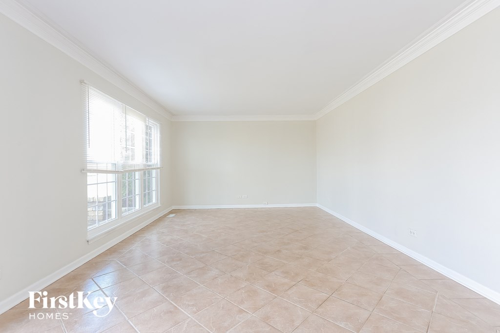 an empty living room with a large window and tiled floors