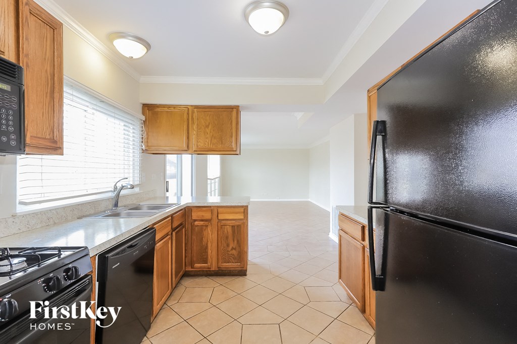 a kitchen with wooden cabinets and a black refrigerator and a sink