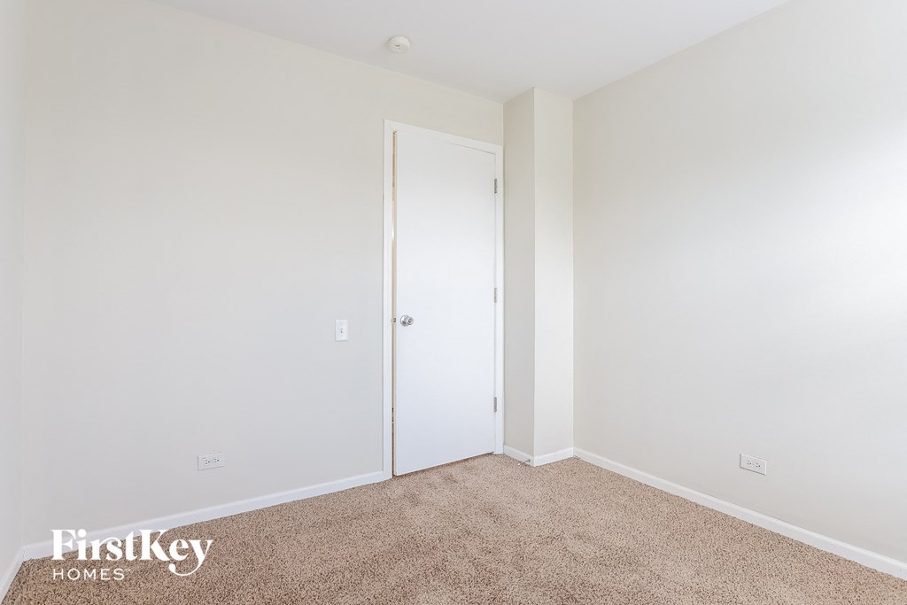 a bedroom with white walls and a door to a closet