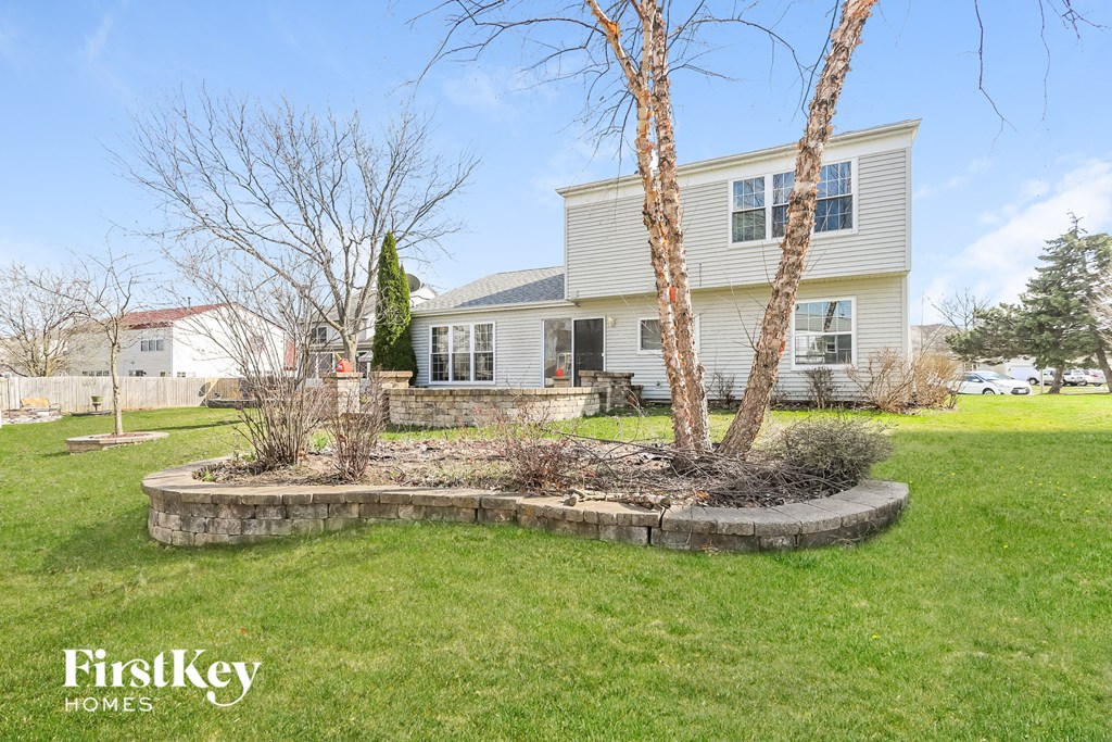 a front yard with two trees and a house in the background