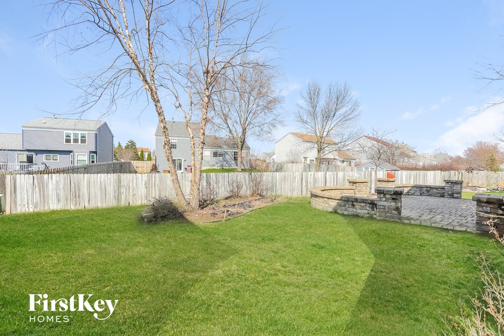a backyard with a fence and a lawn and a tree