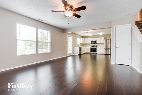 A spacious living room with a ceiling fan and hardwood floors.